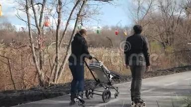 年轻的爸爸和妈妈正在和婴儿车里的婴儿<strong>轮滑</strong>，后景。 <strong>运动</strong>父母在沥青上溜冰
